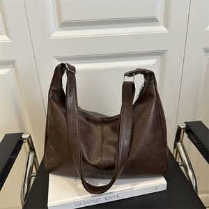 Grand sac cabas vintage marron foncé en similicuir texturé sur une chaise en cuir noir