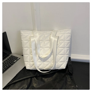 Detail of white quilted tote bag with geometric stitching and nylon shoulder straps