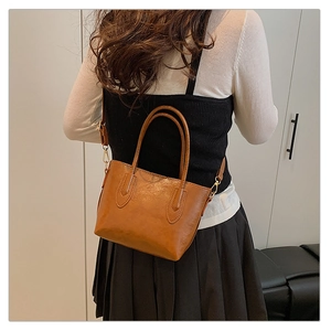 Vue arrière d'un mannequin portant le grand sac cabas en cuir marron et sa bandoulière