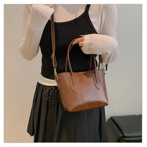 Sac cabas marron minimaliste en cuir avec anses et bandoulière porté par un mannequin