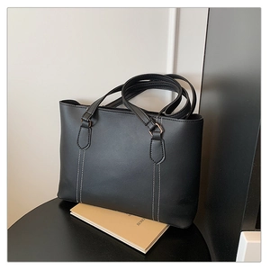 Gros plan sur un sac cabas noir montrant le cuir lisse et les coutures contrastées blanches