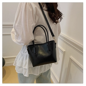 Détail du sac cabas noir avec texture lisse, ferrures dorées et fine bandoulière réglable