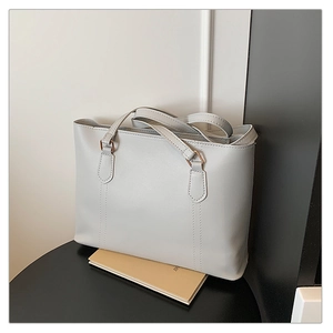 Gros plan détaillé d'un sac cabas gris clair avec coutures verticales et boucles dorées