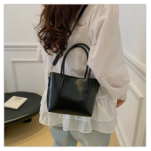 Détail d'un sac cabas noir avec doubles anses et bandoulière amovible en métal doré chic