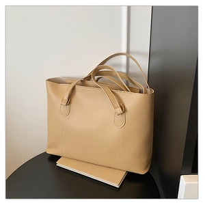 Sac fourre-tout beige minimaliste en cuir lisse posé sur un tabouret noir pour le quotidien