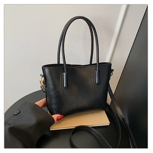 Vue détaillée du cuir synthétique noir et des finitions dorées d'un grand sac cabas