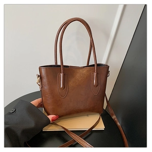 Détail d'un grand sac fourre-tout marron vintage avec double anse et boucles dorées