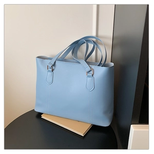 Détail du sac cabas bleu clair avec anneaux dorés et surpiqûres verticales élégantes
