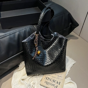 Large black woven leather tote bag with shoulder strap and metallic orb charm details