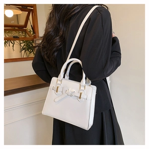 Détail du sac Kelly blanc montrant le nœud décoratif et les accessoires dorés