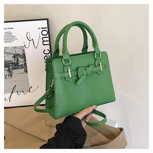 Détail d'un sac à main vert avec boucle à nœud et garnitures dorées