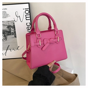 Détail d'un sac à main magenta avec nœud en cuir et boucle en métal doré élégant