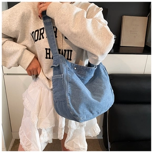 Dettaglio della borsa a tracolla in denim blu con pratica tasca laterale e bottone a scatto