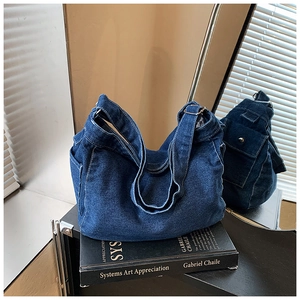 Dettaglio della borsa hobo in denim blu scuro con cuciture bianche su sfondo artistico