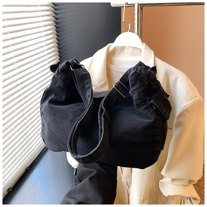 Dettaglio della borsa a tracolla in denim nero con cinturino e fibbia in metallo