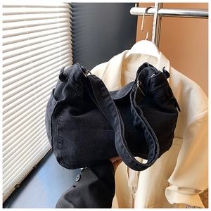 Dettaglio della borsa a tracolla in denim nero lavato con trama vintage e cinturini laterali