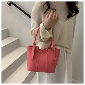 Detail of pink faux leather handbag with contrast stitching and metallic handle loops