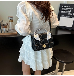 Détail du sac à main noir matelassé avec poignée en foulard de soie et fermoir doré