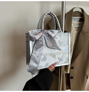 Detail of silver metallic tote bag featuring butterfly embroidery and decorative silk scarf