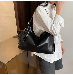Close-up of black leather tote with stylish silver chain mini pouch detail for women