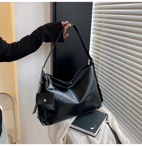 Detail view of black glossy hobo bag with wide shoulder strap and metal chain coin purse