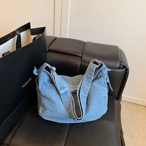 Borsa hobo in denim azzurro su panca in pelle con tracolla larga regolabile