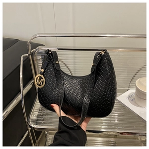 Detail der schwarzen geflochtenen Hobo-Tasche mit goldenem M-Anhänger und feiner Textur