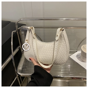Nahaufnahme der cremefarbenen Hobo-Bag mit Flechtmuster und silbernem M-Anhänger