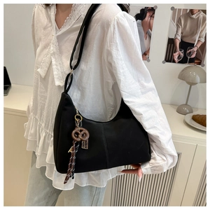 Detail of a black crescent shoulder bag with brown knot and colorful tassel charms