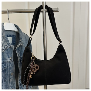 Detail of a black Hobo shoulder bag featuring a stylish woven keychain with gold hardware