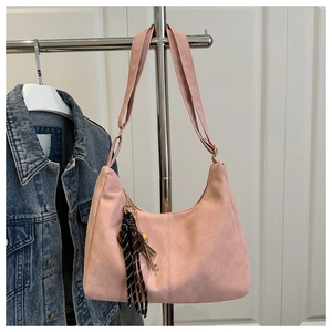 Detail of light pink suede moon bag with vertical stitching and vintage key tassel charm
