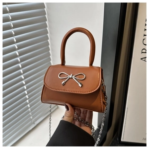 Close-up of a brown micro bag with a silver metal bow accent and slim chain strap