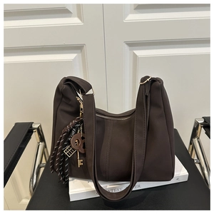 Brown matte hobo shoulder bag with zipper and decorative key pendant on white book