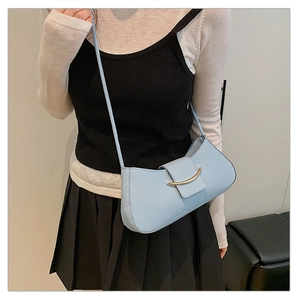 Close-up of light blue crescent shoulder bag with a curved gold metal hardware detail