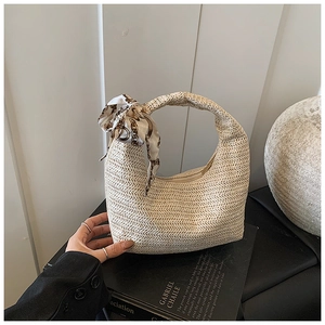 Close-up of beige woven hobo bag with vintage chain print silk scarf handle detail