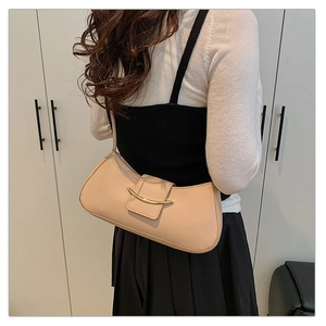 Detailed view of beige leather shoulder bag with elegant gold curved metal clasp