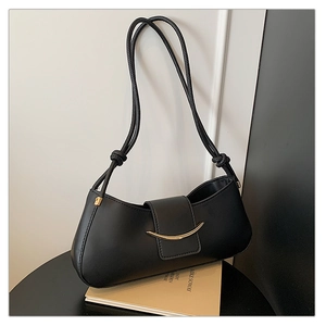 Close-up of the black crescent shoulder bag featuring a sleek gold moon-shaped metal clasp