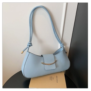 Detail of light blue shoulder bag with golden half-moon buckle and knotted strap