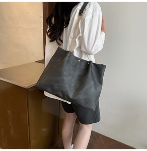 Detail of vintage soft leather tote with gold chain strap and studs on a model
