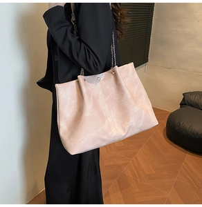 Modern pink tote bag featuring unique marble texture and silver chain strap on model