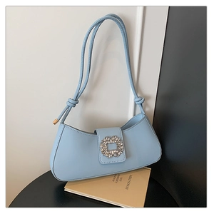 Detailed close-up of light blue shoulder bag with sparkling crystal buckle on textured leather