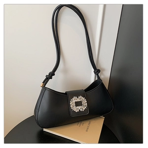 Close-up of black baguette bag with elegant square rhinestone buckle and knotted strap