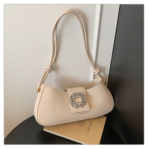 Detail of cream white baguette bag featuring a crystal buckle and knotted strap