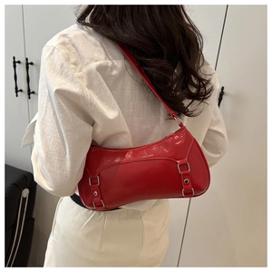 Glossy red faux leather baguette bag with silver buckle worn on a model's shoulder