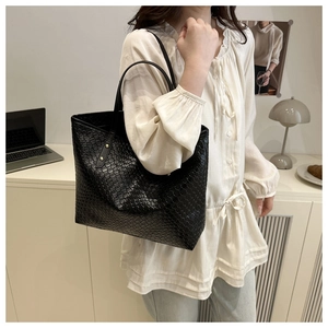 Close-up of black woven tote bag featuring checkerboard pattern and gold buckle detail