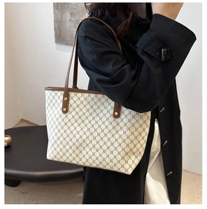 Détail d'un sac cabas en toile monogramme avec anses en cuir marron et rivets dorés