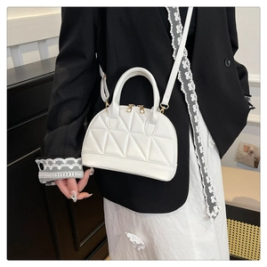 Dettaglio della borsa a conchiglia bianca con trapuntatura geometrica e metallo dorato