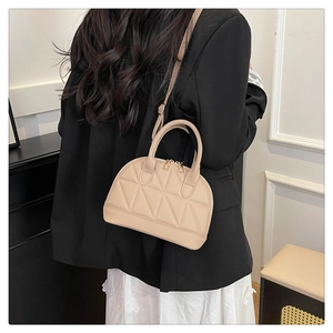Borsa a conchiglia trapuntata beige con motivi a triangolo in vista lifestyle a tracolla