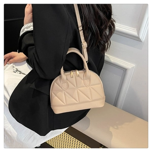 Dettaglio della borsa beige con motivo a rombi trapuntati e cerniere in metallo dorato