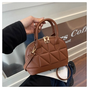 Borsa bowling marrone trapuntata con doppia cerniera dorata tenuta in mano da modella